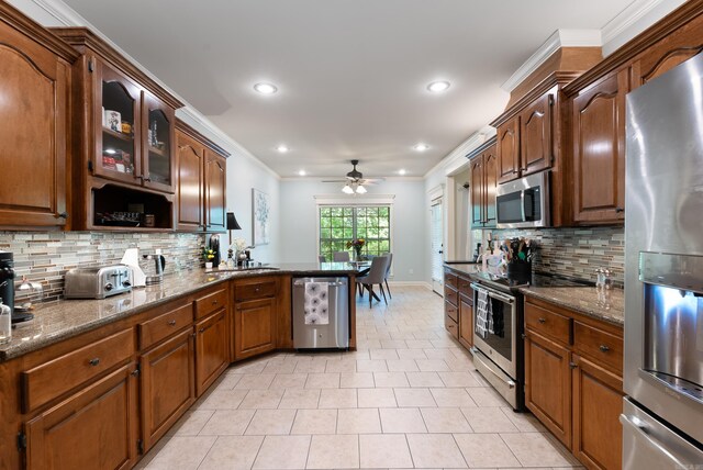 kitchen featuring a ceiling fan, backsplash, light tile patterned floors, dark stone countertops, and stainless steel appliances