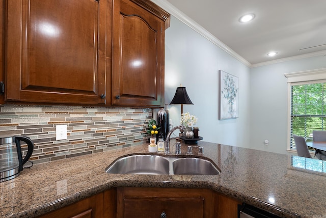 kitchen with crown molding, recessed lighting, tasteful backsplash, a sink, and dark stone countertops