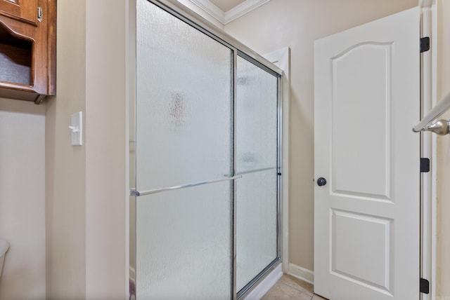 bathroom featuring baseboards, tile patterned flooring, ornamental molding, and a shower stall
