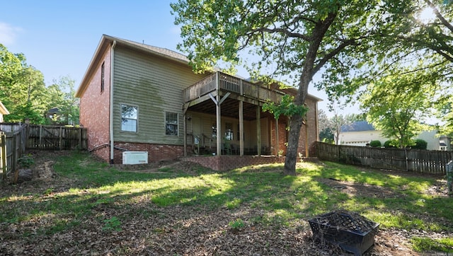 rear view of property featuring a fenced backyard, a yard, and a deck