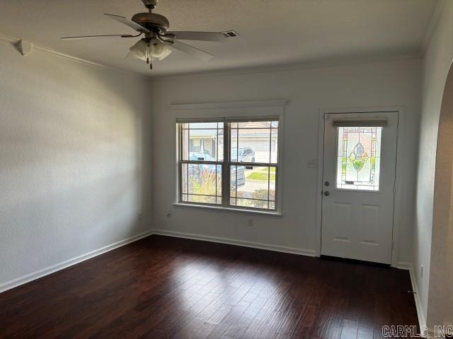 foyer entrance featuring baseboards, ornamental molding, a ceiling fan, and dark wood-type flooring