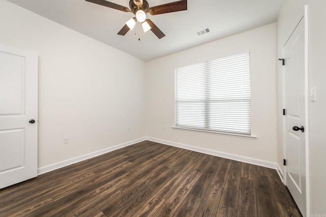 empty room with baseboards, visible vents, ceiling fan, and dark wood-type flooring