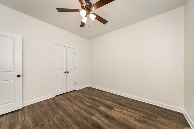 unfurnished bedroom with dark wood-style flooring, a closet, a ceiling fan, and baseboards