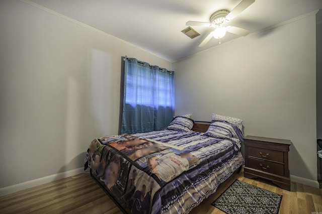 bedroom featuring baseboards, visible vents, ornamental molding, and wood finished floors