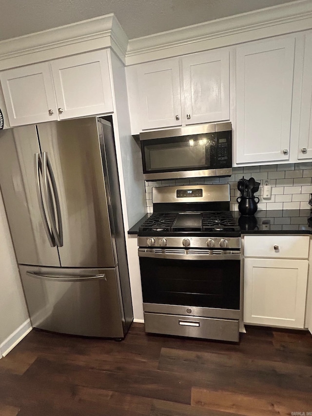 kitchen with dark wood-style floors, decorative backsplash, baseboards, dark countertops, and appliances with stainless steel finishes