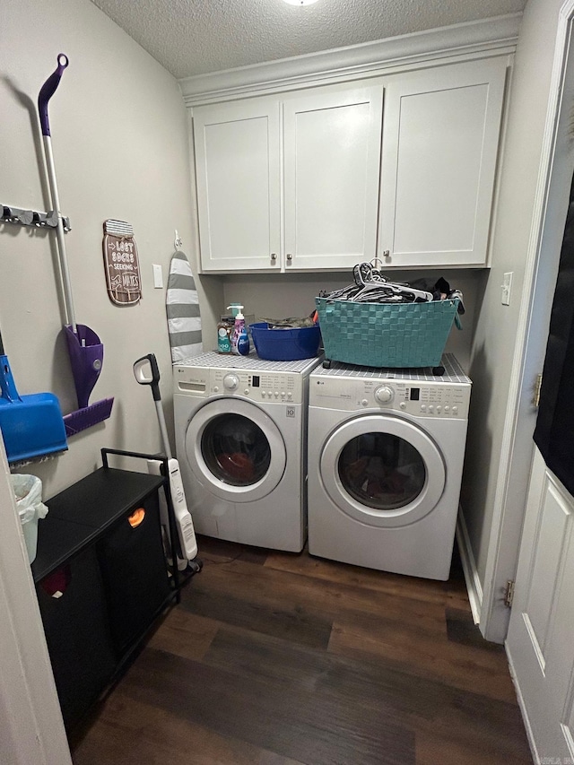 laundry room with a textured ceiling, cabinet space, washing machine and clothes dryer, and dark wood-type flooring