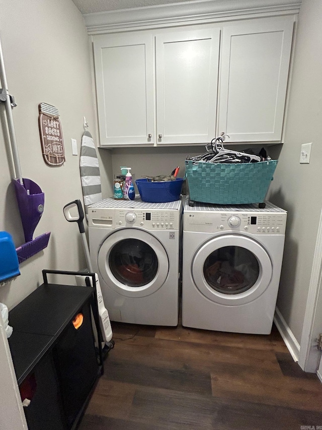 clothes washing area with dark wood-type flooring, washing machine and clothes dryer, and cabinet space