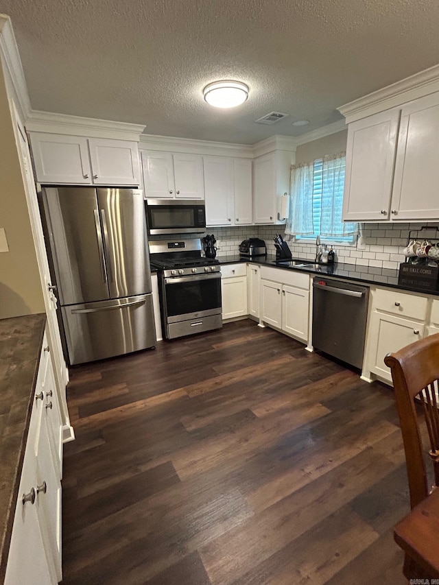 kitchen with stainless steel appliances, dark countertops, and a sink