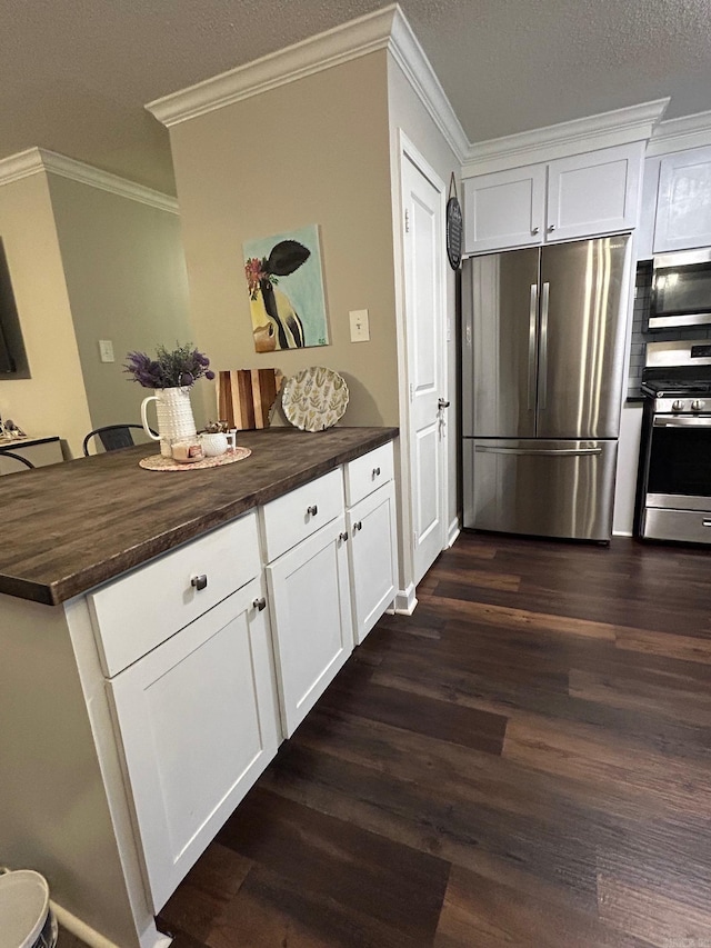kitchen featuring dark wood-style flooring, wood counters, stainless steel appliances, crown molding, and white cabinetry