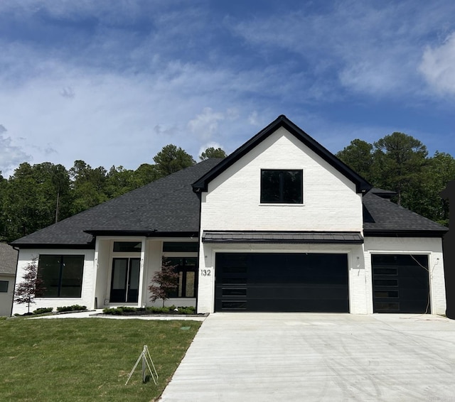 view of front of house featuring brick siding, a front lawn, a shingled roof, and concrete driveway