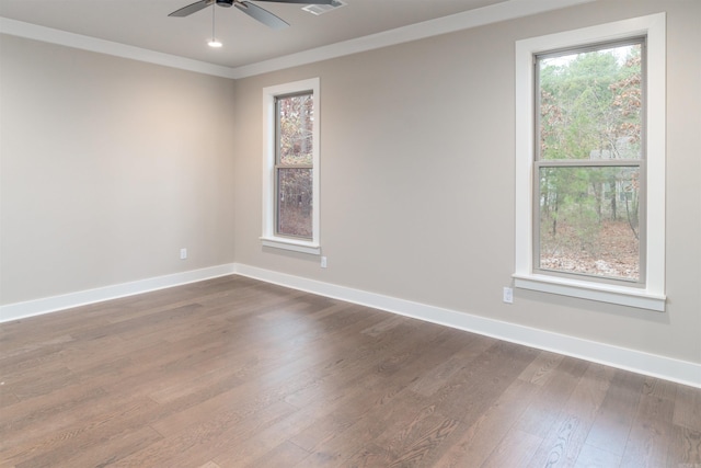 empty room with ornamental molding, ceiling fan, baseboards, visible vents, and dark wood-style floors