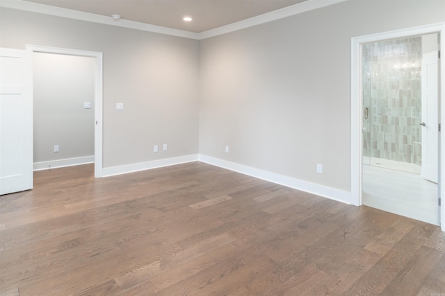 empty room featuring wood finished floors, recessed lighting, ornamental molding, and baseboards
