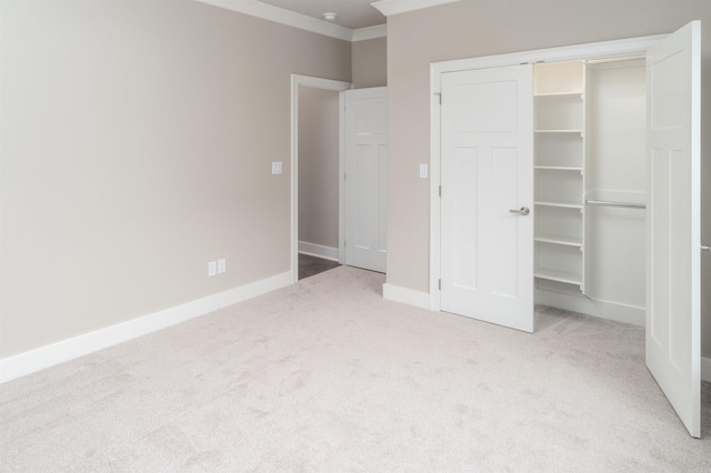 unfurnished bedroom featuring baseboards, ornamental molding, a closet, and carpet flooring