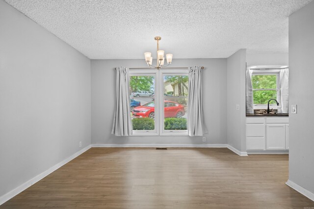 73 Perralena Way, Hot Springs Village, AR 71909 - unfurnished dining area with a textured ceiling, a sink, baseboards, wood finished floors, and a notable chandelier