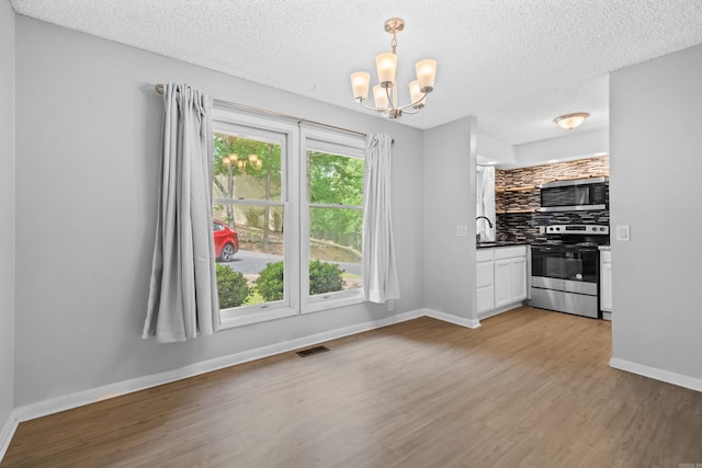 73 Perralena Way, Hot Springs Village, AR 71909 - interior space featuring a sink, a chandelier, decorative backsplash, dark countertops, and appliances with stainless steel finishes