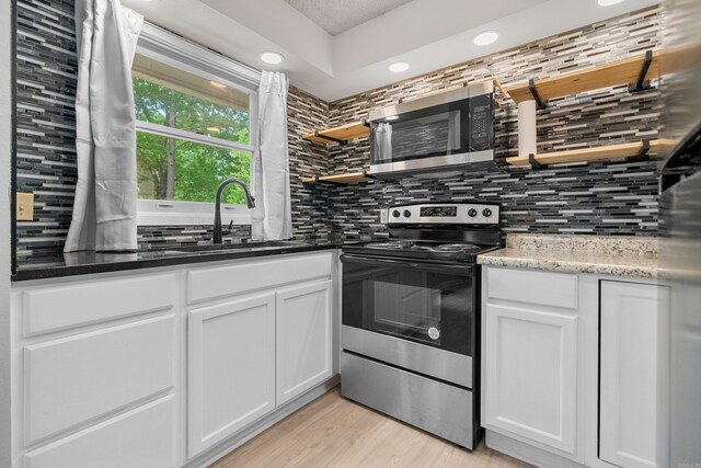 73 Perralena Way, Hot Springs Village, AR 71909 - kitchen featuring decorative backsplash, light wood-style flooring, white cabinets, a sink, and stainless steel appliances