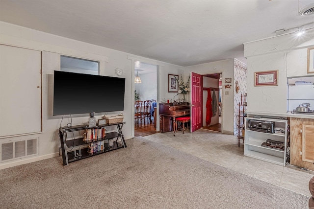 carpeted living area featuring visible vents and tile patterned flooring
