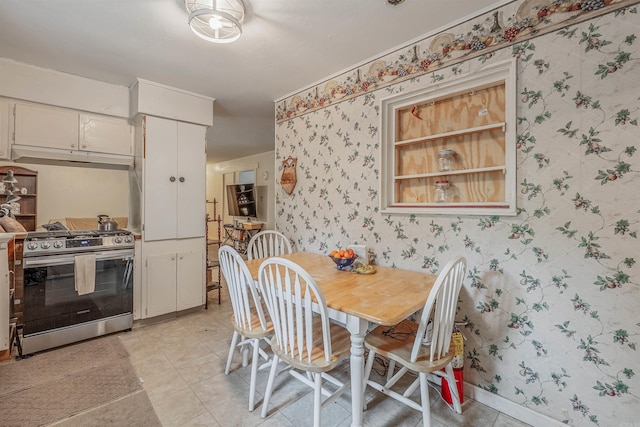 dining area with light tile patterned floors, wallpapered walls, and baseboards