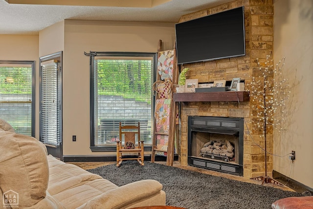 living area with a textured ceiling, a large fireplace, and baseboards