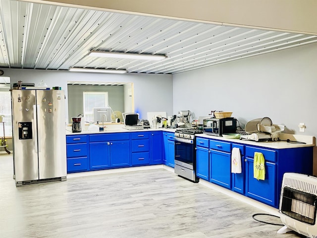 kitchen featuring light wood finished floors, heating unit, stainless steel appliances, and blue cabinetry
