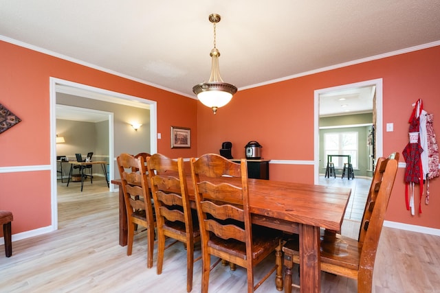 dining space with ornamental molding, light wood-style flooring, and baseboards