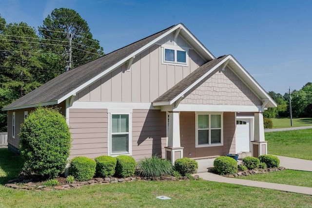 craftsman house with a front yard, a garage, covered porch, board and batten siding, and roof with shingles