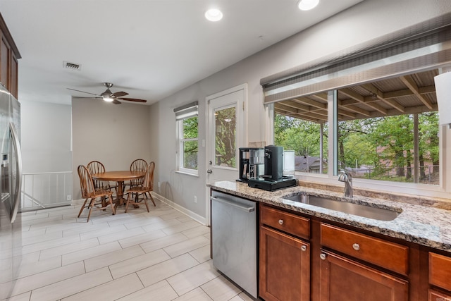 kitchen featuring light stone countertops, appliances with stainless steel finishes, a sink, baseboards, and visible vents