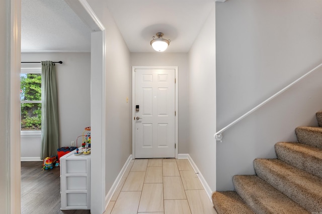 foyer with stairway, light wood-style floors, and baseboards