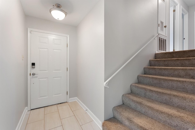 foyer entrance featuring stairway, light tile patterned flooring, and baseboards