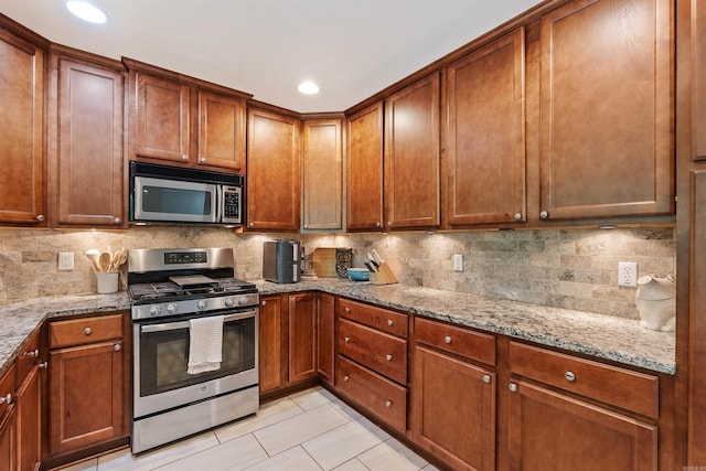 kitchen with tasteful backsplash, stainless steel appliances, light tile patterned flooring, and light stone counters