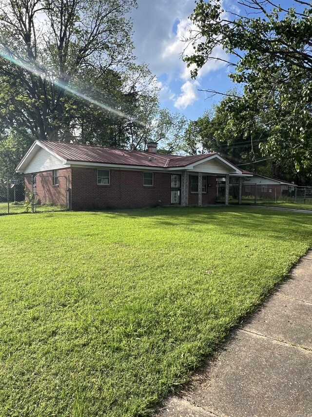 904 Belmont Dr, Pine Bluff, AR 71601 - back of property featuring a lawn, fence, metal roof, and brick siding