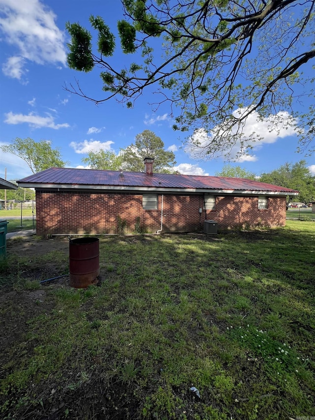 904 Belmont Dr, Pine Bluff, AR 71601 - rear view of house with brick siding, metal roof, a yard, central AC, and a chimney