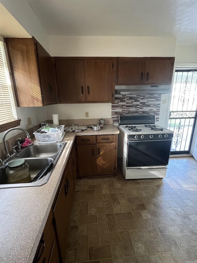 904 Belmont Dr, Pine Bluff, AR 71601 - kitchen featuring tasteful backsplash, gas range, light countertops, a sink, and brick patterned floor