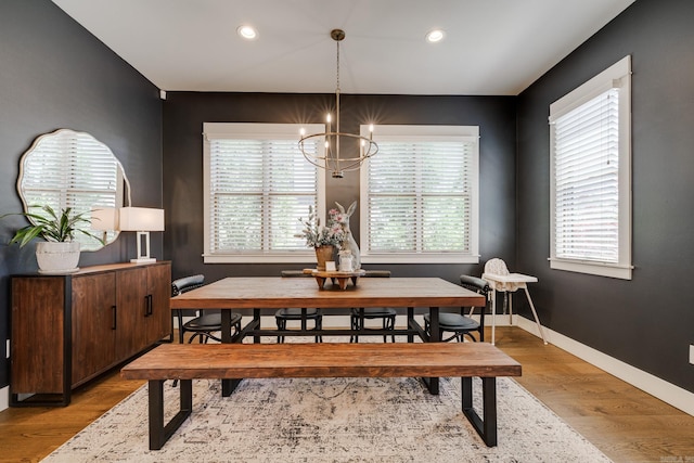 dining space featuring baseboards, light wood-type flooring, a notable chandelier, and plenty of natural light