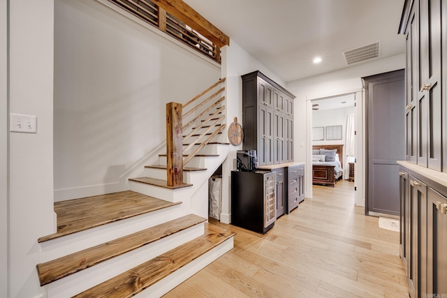 stairway with baseboards, visible vents, wood finished floors, and recessed lighting