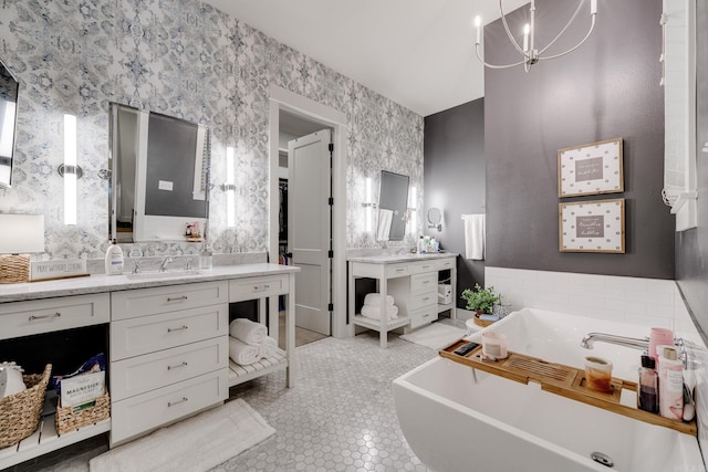 full bath featuring vanity, a freestanding bath, wallpapered walls, and a chandelier