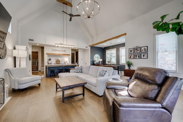 living room with a chandelier, visible vents, light wood finished floors, and high vaulted ceiling