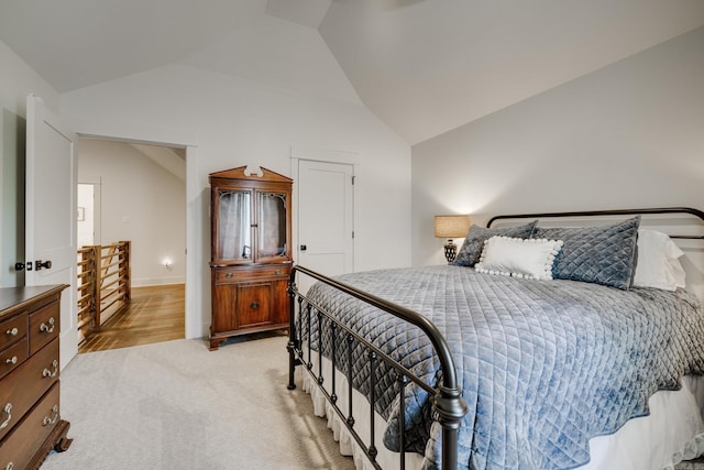 bedroom featuring light carpet, lofted ceiling, and baseboards
