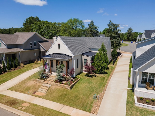 bungalow-style home with driveway, a standing seam roof, metal roof, covered porch, and a front yard