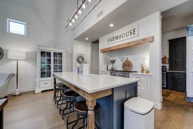 kitchen featuring wood finished floors, light stone counters, backsplash, a center island, and a kitchen breakfast bar