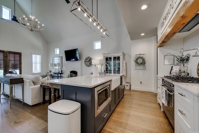 kitchen featuring high vaulted ceiling, stainless steel appliances, light stone countertops, and a sink