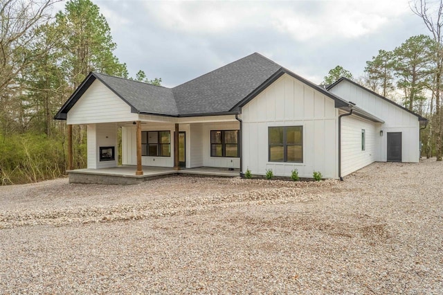 view of front facade with driveway, covered porch, board and batten siding, and a shingled roof