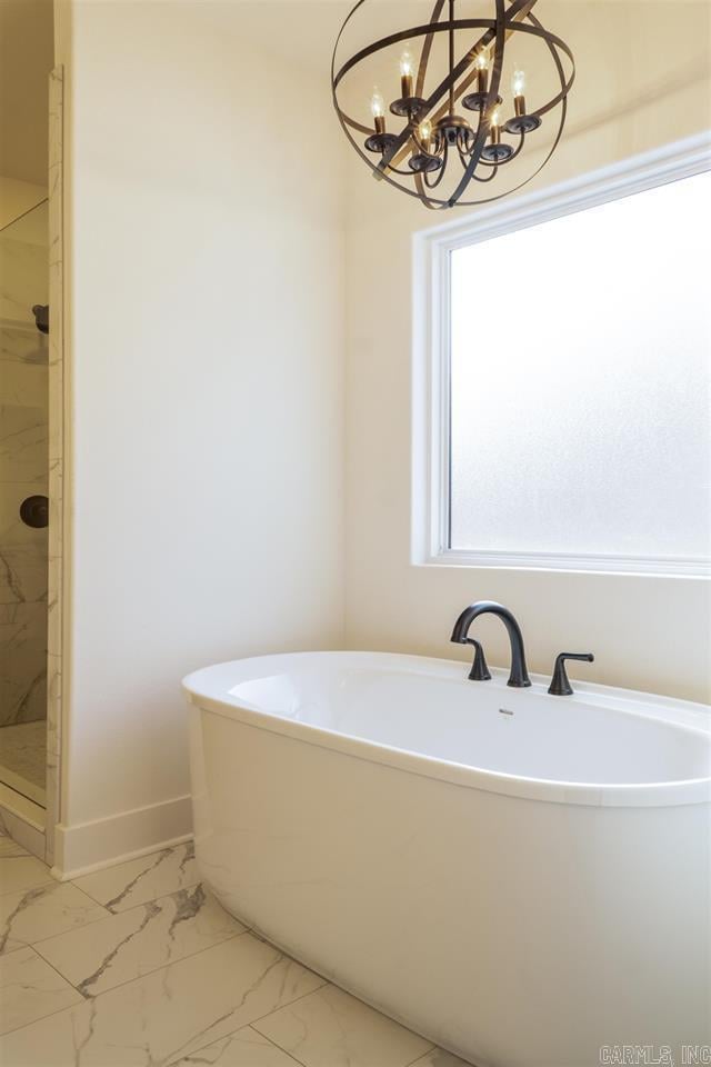 bathroom featuring baseboards, an inviting chandelier, a marble finish shower, a freestanding tub, and marble finish floor