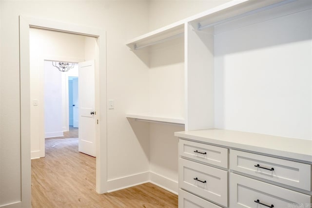 walk in closet featuring a chandelier and light wood finished floors