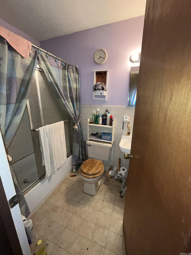 bathroom featuring tile patterned floors, wainscoting, tile walls, toilet, and curtained shower