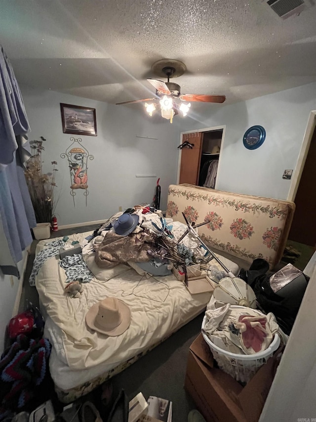 bedroom featuring a textured ceiling, visible vents, and a ceiling fan