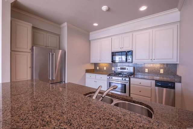 kitchen with dark stone countertops, appliances with stainless steel finishes, ornamental molding, backsplash, and a sink