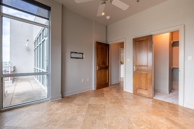 unfurnished room with a towering ceiling, ceiling fan, and baseboards