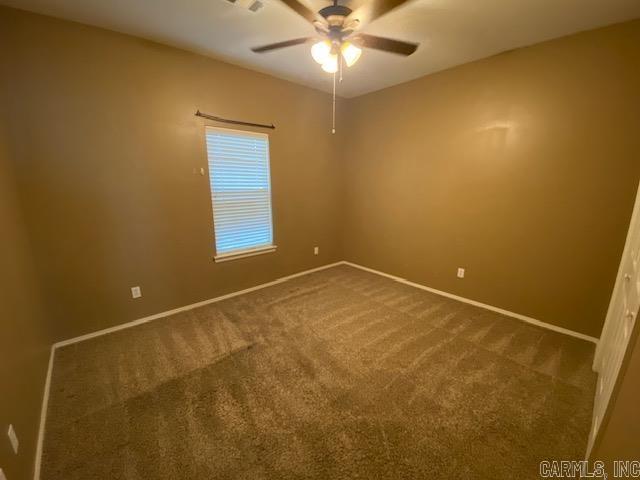 unfurnished room featuring dark carpet, ceiling fan, and baseboards