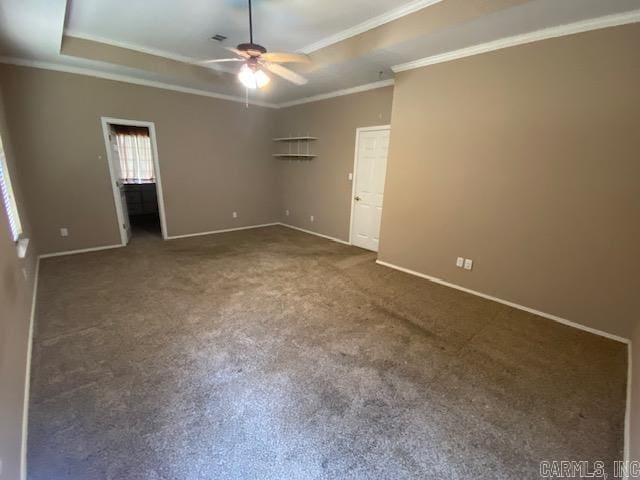 carpeted spare room featuring ornamental molding, a ceiling fan, a tray ceiling, and baseboards